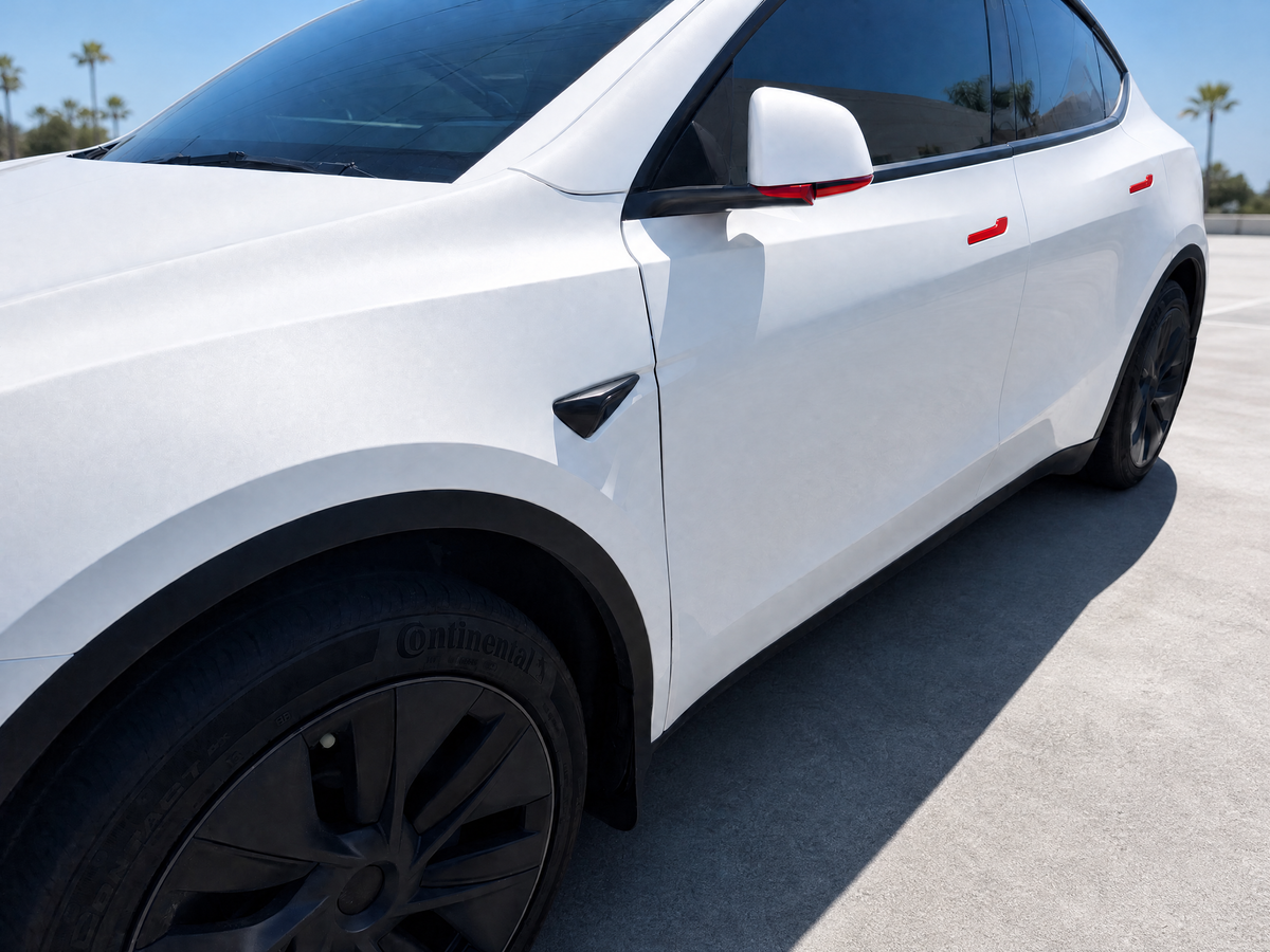 White Tesla Model Y with gloss red accent wrap on the door handles and side mirrors